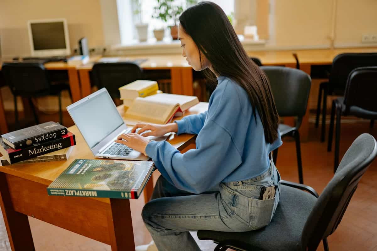 A Woman in a Blue Sweater Typing on a Laptop